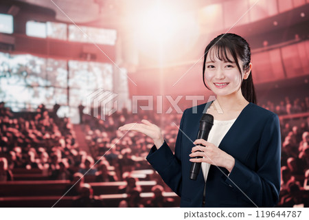 Woman speaking in front of a large audience 119644787