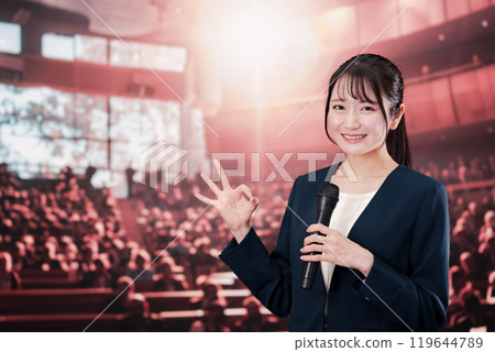 Woman speaking in front of a large audience 119644789