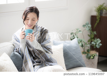 Cute woman drinking hot coffee or drink in room Autumn/winter relaxing image Wide angle 119645097
