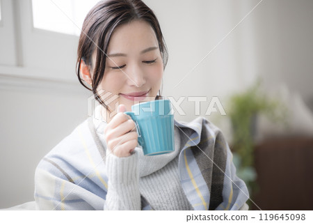 Close-up of a woman drinking hot coffee or beverage in the room 119645098