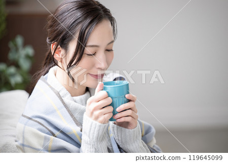一位女士在房間裡喝著熱咖啡或飲料的特寫 一位女士在房間裡喝著熱咖啡或飲料的特寫 119645099