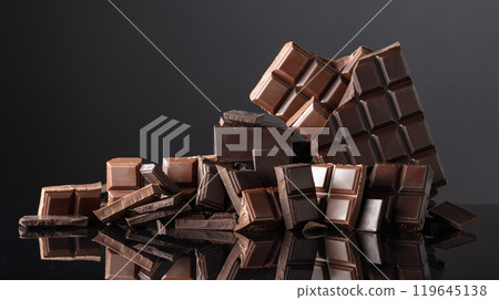 Broken bitter and milk chocolate bars on a black background. 119645138