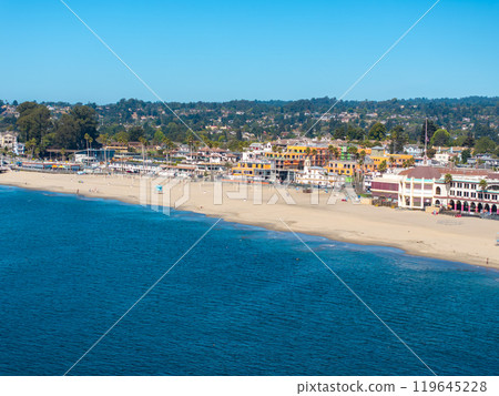 Aerial view of Santa Cruz, California, featuring the beachfront, iconic boardwalk, sandy beach, deep blue ocean, and town buildings against lush hills. 119645228