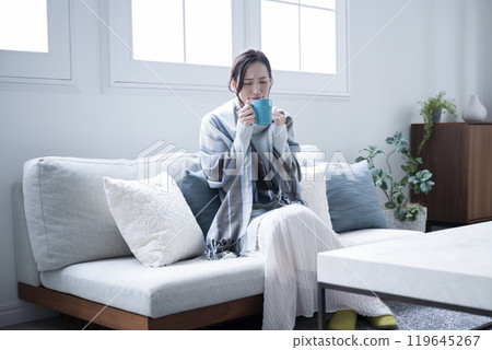 Do I have a cold? A woman drinking a hot drink, feeling chilly, perhaps due to the beginning of a cold. Wide-angle Do I have a cold? A woman drinking a hot drink, feeling chilly, perhaps due to the beginning of a cold. Wide-angle 119645267