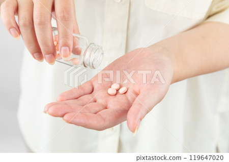 Woman taking medicine out of a bottle 01 119647020