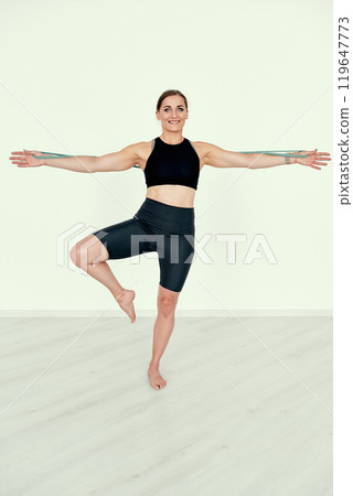 Fitness Trainer Demonstrating Resistance Band Stretch 119647773
