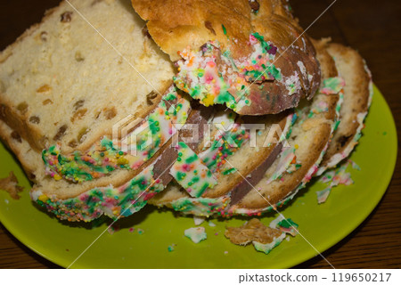 Festive bread with colorful sprinkles and icing on green plate 119650217