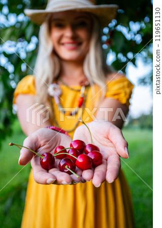 Farmer Woman Offering Freshly Picked Red Cherries in Outstretched Hands on a Warm Summer Day 119651130