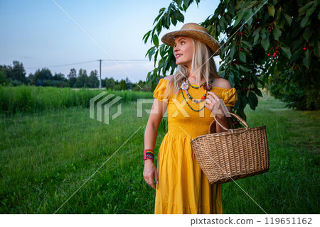 Smiling Woman Picking Ripe Cherries by a Tree with Green Leaves on a Beautiful Sunny Spring Day Smiling Woman Picking Ripe Cherries by a Tree with Green Leaves on a Beautiful Sunny Spring Day 119651162