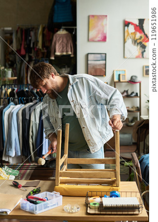 Man hitting side of seat of wooden chair Man hitting side of seat of wooden chair 119651986