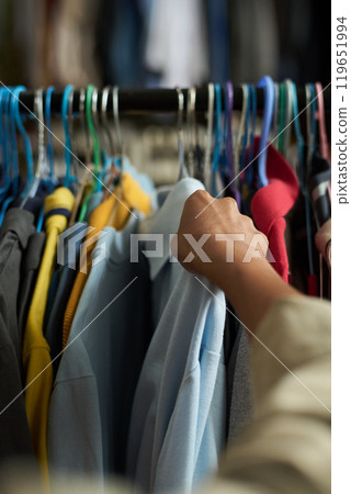 Taking hangers with shirt from rack 119651994