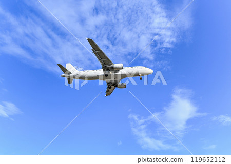 Passenger plane landing at the airport, under a blue sky with white clouds 119652112