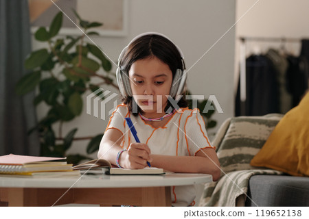 Focused Girl Wearing Headphones Studying in Living Room Focused Girl Wearing Headphones Studying in Living Room 119652138