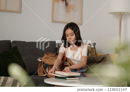 Young Girl Reading Book in Cozy Living Room 119652147