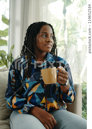 Smiling Woman Relaxing While Holding Coffee Mug Smiling Woman Relaxing While Holding Coffee Mug 119652584