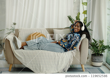 Relaxing on Couch Listening to Music with Headphones Relaxing on Couch Listening to Music with Headphones 119652586