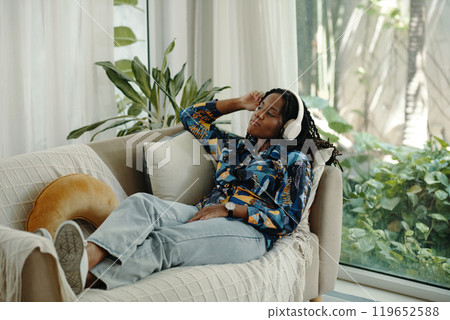 Relaxing on Couch While Listening to Headphones Relaxing on Couch While Listening to Headphones 119652588