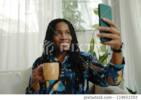 Holding Smartphone and Drinking Coffee in Living Room Holding Smartphone and Drinking Coffee in Living Room 119652593