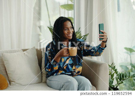Smiling Woman Taking Selfie While Holding Coffee Cup Smiling Woman Taking Selfie While Holding Coffee Cup 119652594