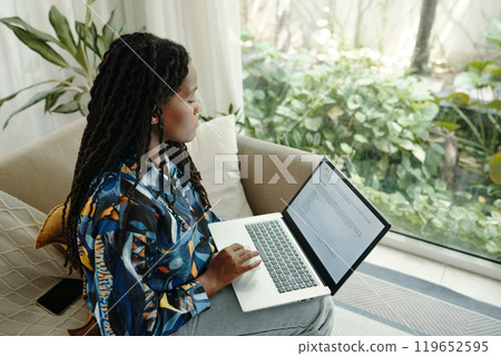 Woman Engaging with Laptop in Bright Living Room Woman Engaging with Laptop in Bright Living Room 119652595