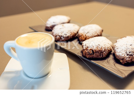 Pane dei Morti cookies with powdered sugar on dark plate in focus with blurred espresso in front Pane dei Morti cookies with powdered sugar on dark plate in focus with blurred espresso in front 119652765
