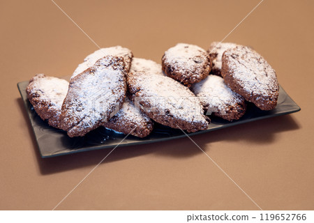 Stack of Pane dei Morti cookies with powdered sugar on dark plate showcasing rustic Italian texture 119652766