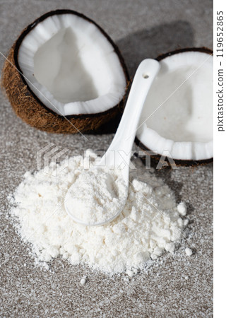 Coconut flour among coconut halves on gray stone background. 119652865