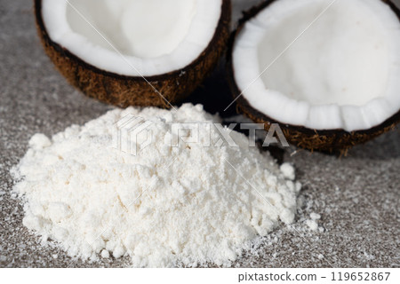 Coconut flour among coconut halves on gray stone background. 119652867