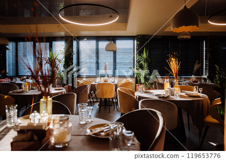Elegant restaurant interior with natural light, cozy decor, and stylish table settings 119653776