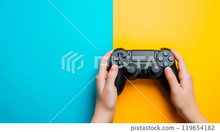 Gamer holding black game controller on colorful background 119654182