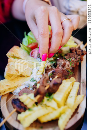 Tasty kebab with fries, pita bread, and sauce, a perfect combination for a delicious meal Tasty kebab with fries, pita bread, and sauce, a perfect combination for a delicious meal 119655291