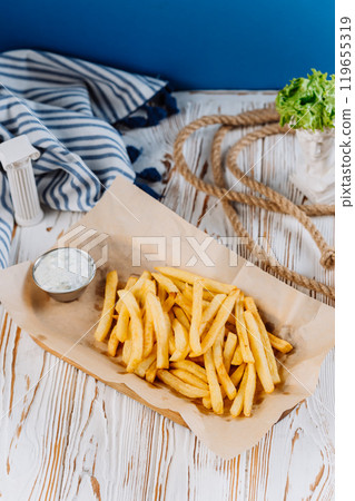 Golden French fries with a side of creamy dip, perfect for snack lovers 119655319