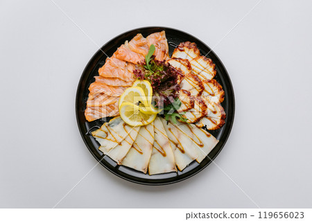 Gourmet seafood platter with salmon, white fish, and chicken slices garnished with lemon and greens Gourmet seafood platter with salmon, white fish, and chicken slices garnished with lemon and greens 119656023