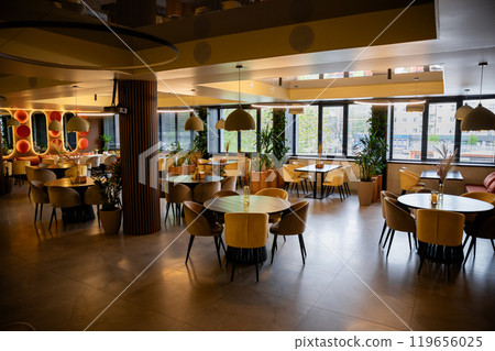 Elegant restaurant interior with natural light, cozy decor, and stylish table settings 119656025