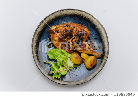 Juicy roasted chicken with black pepper, grilled potatoes, and fresh greens, elegantly plated 119656040