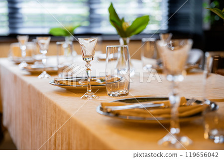 Elegant table setting with sunlight reflections creating a serene and warm dining experience Elegant table setting with sunlight reflections creating a serene and warm dining experience 119656042