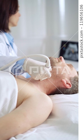 Doctor performing neck ultrasound exam on male patient Doctor performing neck ultrasound exam on male patient 119656106