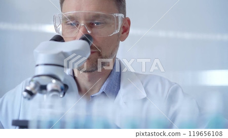 Man scientist with protective glasses and gloves is using micros Man scientist with protective glasses and gloves is using micros 119656108