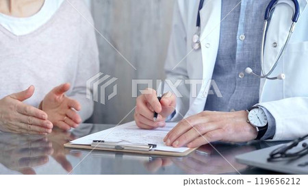 Doctor man and woman patient are discussing something and gesturing with their hands in medical office, close up. Medicine concept Doctor man and woman patient are discussing something and gesturing with their hands in medical office, close up. Medicine concept 119656212