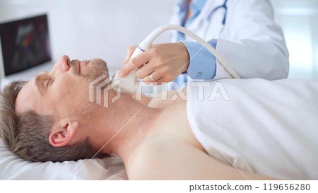 Doctor woman performing neck ultrasound exam on male patient. Medicine and health care 119656280