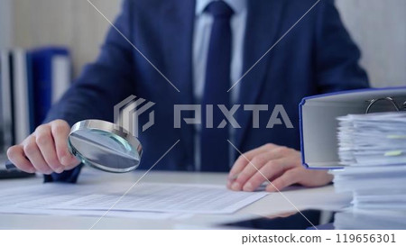 Businessman is carefully examining financial documents with a magnifying glass, highlighting the importance of thorough analysis in business. Audit and taxes Businessman is carefully examining financial documents with a magnifying glass, highlighting the importance of thorough analysis in business. Audit and taxes 119656301