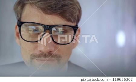 Businessman with glasses looking intently obscured partially by a translucent surface of laptop. Business concept Businessman with glasses looking intently obscured partially by a translucent surface of laptop. Business concept 119656302