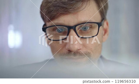 Businessman with glasses looking intently obscured partially by a translucent surface of laptop. Business people concept Businessman with glasses looking intently obscured partially by a translucent surface of laptop. Business people concept 119656310