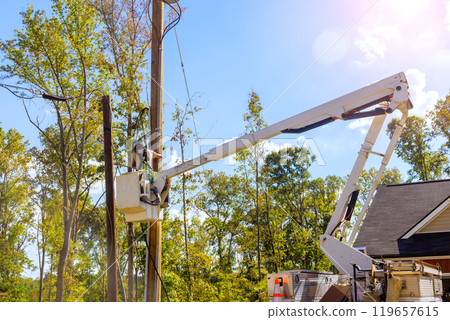 Lineman performing overhead electrical maintenance using bucket lift truck 119657615
