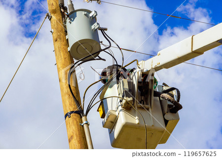 Bucket truck supports worker attending to electrical infrastructure on pole after hurricane Bucket truck supports worker attending to electrical infrastructure on pole after hurricane 119657625