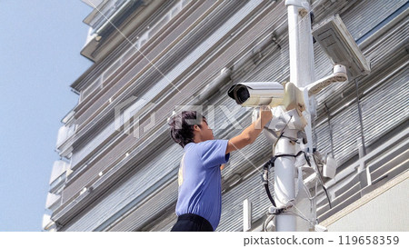 Man working on outdoor surveillance camera 119658359