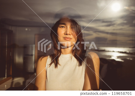 Woman looking out through the glass window which reflecting the sea view. Woman looking out through the glass window which reflecting the sea view. 119658701