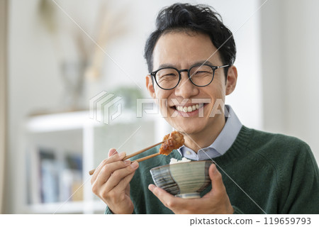 一名 40 歲左右的男子吃著炸雞，看著鏡頭 119659793