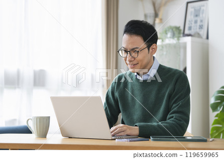 A man in his late 30s working on a laptop computer, working from home, image 119659965