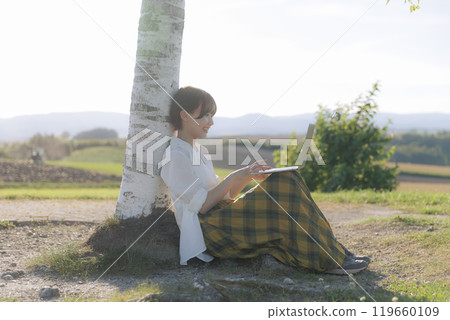 A young woman sitting on a bench and using a laptop A young woman sitting on a bench and using a laptop 119660109